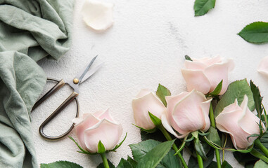 Top view of a bouquet of pink roses, scissors and fabric
