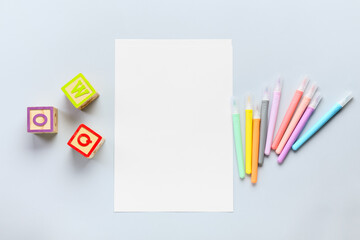 Blank paper sheet with felt-tip pens and cubes on light background