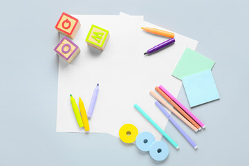 Blank paper sheets with felt-tip pens, sticky notes and children toys on light background