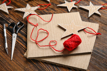 Christmas cardboard stars with scissors and thread on dark wooden background, closeup