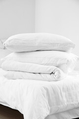 Stack of pillows and blanket on comfortable bed in light bedroom