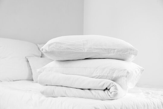 Stack of pillows and blanket on comfortable bed in light bedroom