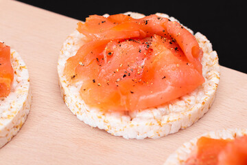 Tasty Rice Cake Sandwiches with Fresh Salmon Slices on Cutting Board - Close-Up. Easy Breakfast and Diet Food. Crispbread with Red Fish. Healthy Dietary Snack