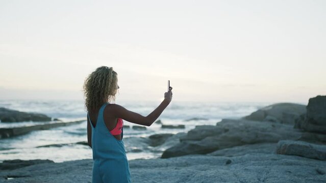 Woman, phone and photo of beach, panorama view and sky landscape in nature, earth day and summer vacation. Travel, tourism and tourist with smartphone to record ocean, sunset and horizon at calm sea