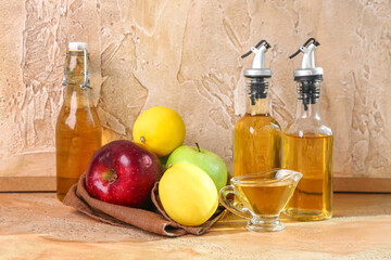 Fruits, gravy boat and bottles of apple cider vinegar on color table