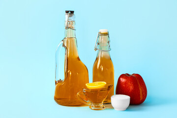 Bottles of apple cider vinegar and sugar on color background