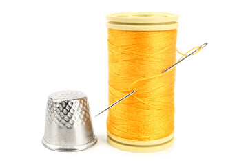 Thread spool with needle and thimble on white background