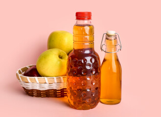 Bottles of fresh apple juice and basket with fruits on color background