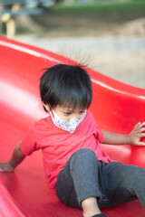 Asia child smiling playing on slider bar toy outdoor playground, happy preschool little kid having funny while playing on the playground equipment in the daytime in summer.