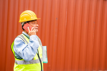 A senior specialist engineer is on the phone with an employee of a container shipping company. Logistics global cargo container concept.