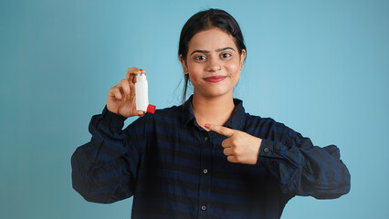 Portrait of a cheerful young woman holding asthma inhaler, Asian Indian girl with inhaler isolated...