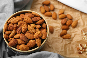 Bowl of almonds and sliced nuts on brown background