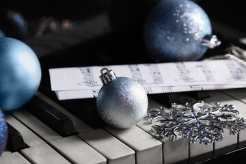 Christmas balls with note sheet on piano keys, closeup