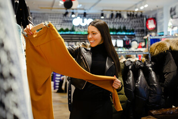 Woman holding looking at new trousers in her hands while buying clothes in the store
