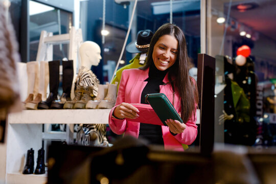 Beautiful woman shopping for new colorful stylish leather wallet in fashion boutique.