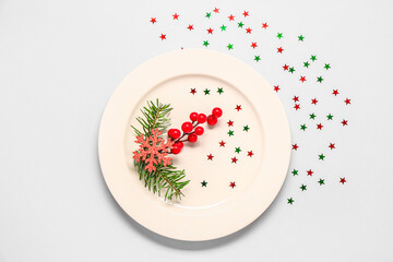 Plate with Christmas branches, snowflake, cranberry and stars on light background