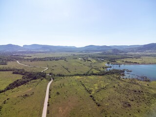 Obraz premium Aerial view on mountain lake. Drone over water reservoir at mountain valley covered with green spring forest. Beautiful view from above on smooth blue surface of mountain lake among highlands. Nobody