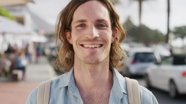 Travel, happy and face of a man in the city while on a summer vacation walking in the street. Happiness, tourism and portrait of young guy with freedom in a town on adventure on holiday in Australia.