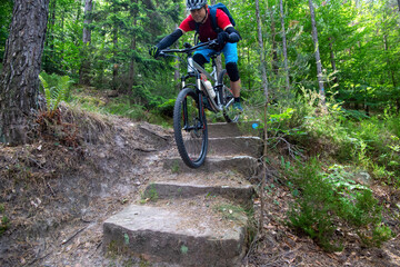 Naklejka premium Mountainbiker fährt Treppenstufen auf einem schwierigen Singletrail 