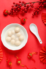 Bowl of tasty tangyuan and Chinese decor on red background. Dongzhi Festival