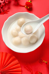 Bowl of tasty tangyuan and Chinese decor on red background. Dongzhi Festival
