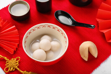 Bowl of tasty tangyuan and Chinese decor on red mat. Dongzhi Festival