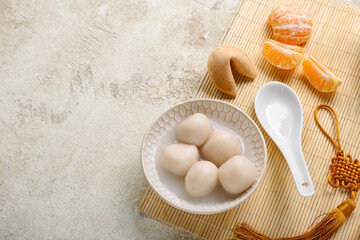 Mat with bowl of tangyuan, fortune cookie and mandarins on grunge background. Dongzhi Festival