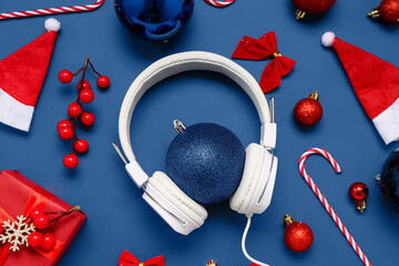 Headphones with Christmas decor, Santa hats and gift on blue background