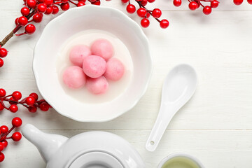 Bowl of tangyuan with teapot berries on white wooden background. Dongzhi Festival