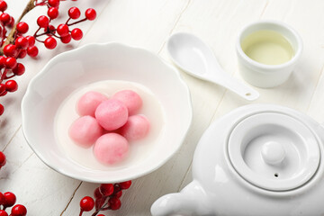 Bowl of tangyuan with teapot, cup and berries on white wooden background. Dongzhi Festival