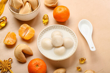 Bowl of tangyuan with fortune cookies and mandarins on beige background. Dongzhi Festival