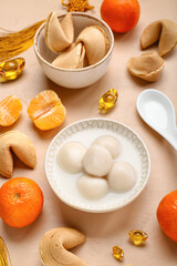 Bowl of tangyuan with fortune cookies and mandarins on beige background. Dongzhi Festival