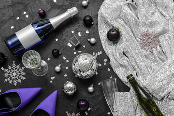 Bottles of champagne, glasses, Christmas decor, heels and dress on dark background
