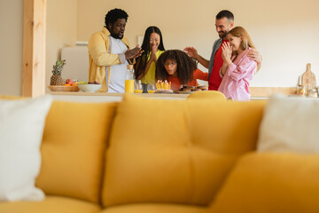 Diverse multiracial group of excited friends giving a cake to a happy young woman at her birthday...