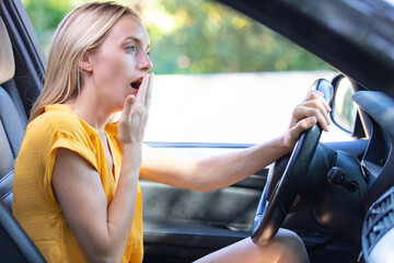 tired woman yawning while she is driving - obrazy, fototapety, plakaty