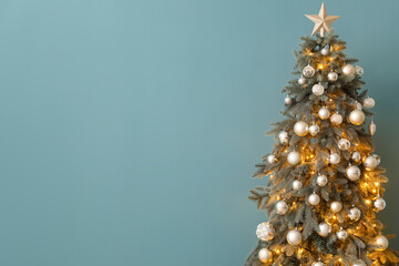 Glowing Christmas tree near blue wall