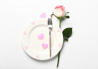 Table setting for Valentine's Day with pink hearts and rose on white background