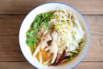 Thai food thai rice noodles spicy soup curry with fresh vegetable, Rice noodles with chicken feet on soup bowl on wooden table food background