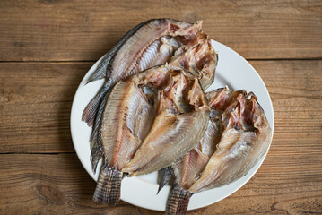 dried fish on white plate, tilapia fish for cooking food on wooden - food preservation dry fish
