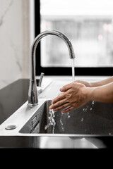 person washing hands in kitchen sink