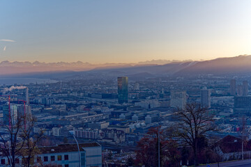 Aerial view over City of Zürich with skyscraper Prime Tower and Swiss Alps in the background on a sunny autumn evening. Photo taken December 6th, 2022, Zurich, Switzerland.