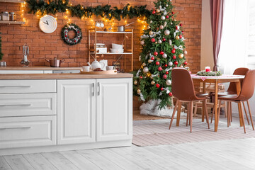 Interior of kitchen with Christmas tree, white counters and dining table