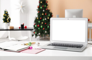 Laptop with Christmas balls on table in office
