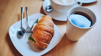 Croissant and meat on a girl's table at lunchtime.