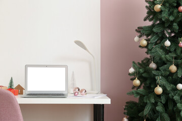 Laptop with Christmas gifts on table in office
