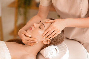Obraz na płótnie Canvas Pretty young woman receiving face massage in beauty salon
