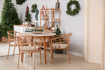 Dining table with Christmas branches in interior of kitchen