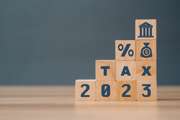 Tax burden icon on wooden block. 2023 tax concept, paying taxes, 2023, paying tax rates, collecting taxes.