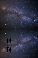 Obraz na płótnie Canvas 天の川と満天の星空が水面に映り込む湖でデートするカップルのシルエット 