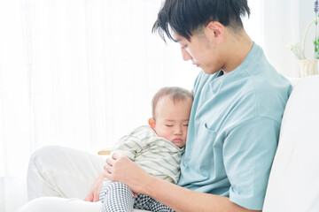 Fototapeta na wymiar 家で眠る赤ちゃんを抱っこする父親